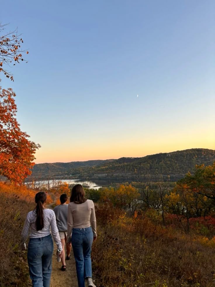 Friends walking a trail toward a valley overlook at golden hour