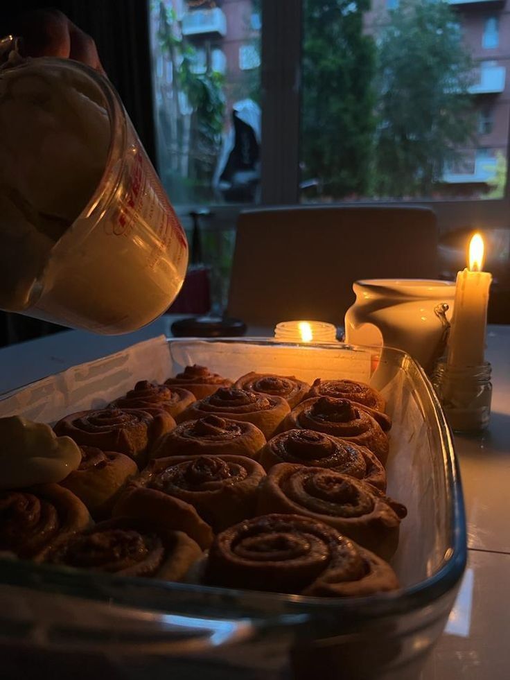 Fresh cinnamon rolls being frosted on a tray