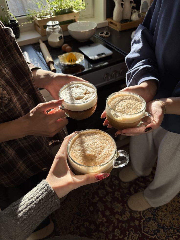 Three hands raising frothy lattes together